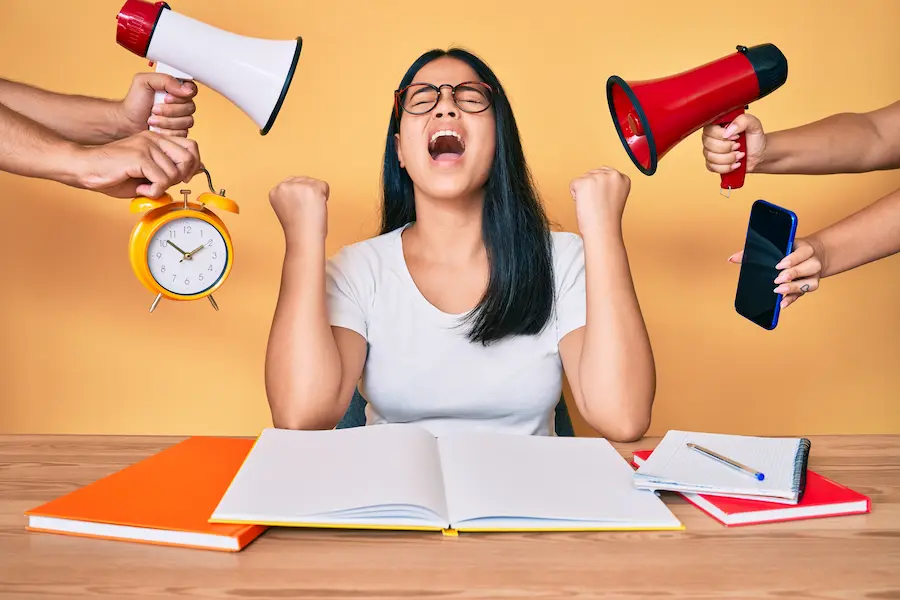 Studenta zdenerwowana bo zbliża się egzamin na studia. wokół megafony i budziki